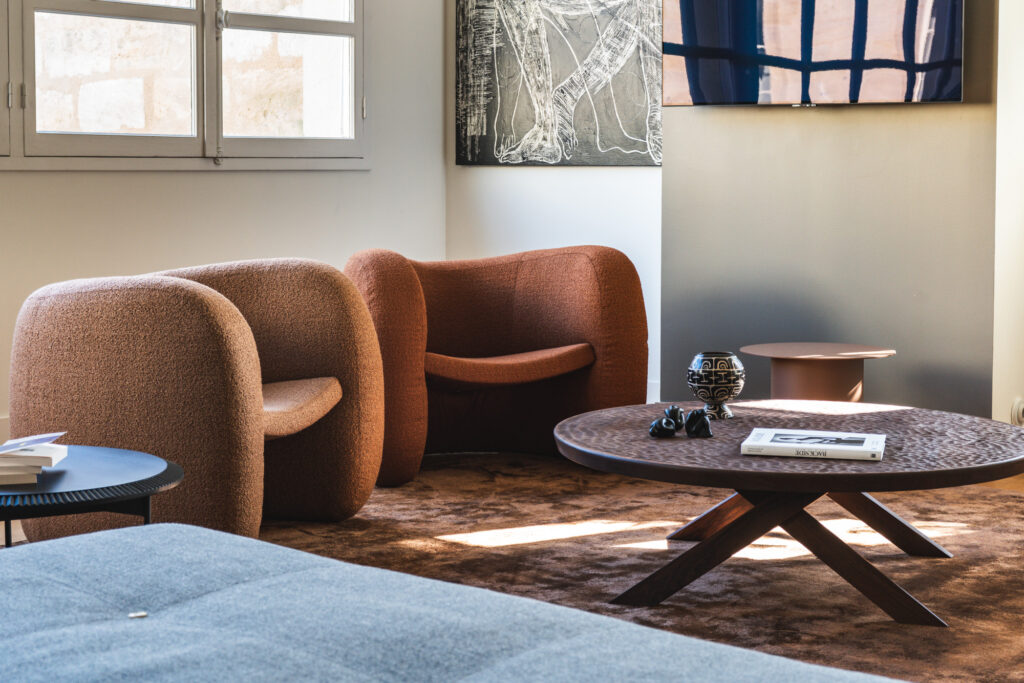 Salon rénové par De Boysson Design à Bordeaux, fauteuils en bouclette terracotta et table basse en bois sculpté